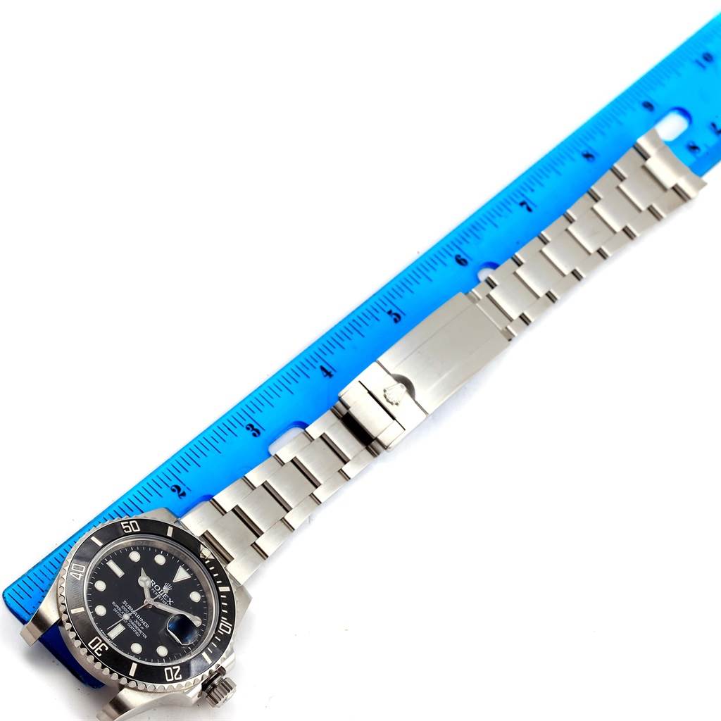 This image shows a Rolex Submariner 116610 Men's Stainless Steel Black Dial 116610 Men's Stainless Steel Black Dial watch laid flat with a ruler for scale, showcasing its silver bracelet and black dial.