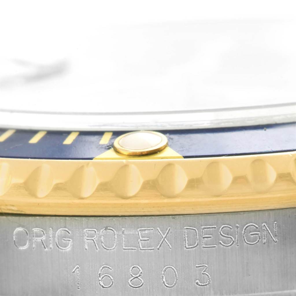 This image shows a close-up of the bezel and engraved case side of a Rolex Submariner 16803 Men's Steel and Gold (two tone) Blue Dial 16803 Men's Steel and Gold (two tone) Blue Dial model 16803.