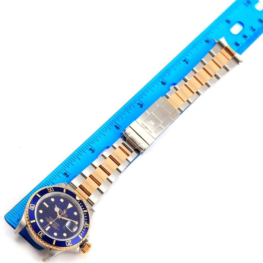 The Rolex Submariner 16803 Men's Steel and Gold (two tone) Blue Dial 16803 Men's Steel and Gold (two tone) Blue Dial watch is displayed flat with its face and bracelet against a ruler.