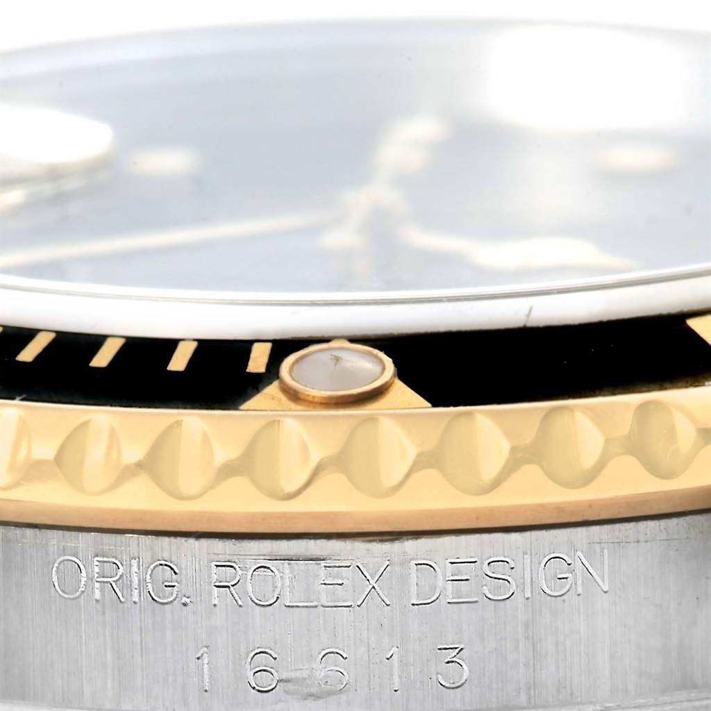Close-up of a Rolex Submariner 16613 Men
s Steel and Gold (two tone) Black Dial 16613 Men
s Steel and Gold (two tone) Black Dial showing the bezel and side with "Orig. Rolex Design" engraving and model number.