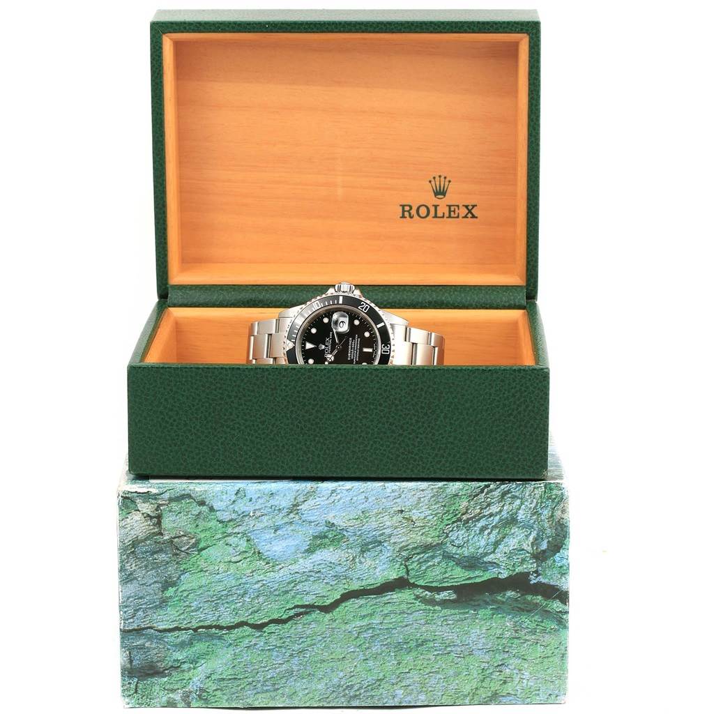The Rolex Submariner 16610 Men's Stainless Steel Black Dial 16610 Men's Stainless Steel Black Dial watch is shown front-facing inside its green and wooden display box with the lid open.