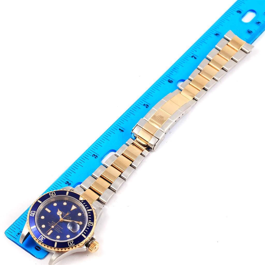 The image shows a Rolex Submariner 16613 Steel and Gold (two tone) Blue Dial 16613 Steel and Gold (two tone) Blue Dial watch, with a blue face and gold accents, laid flat alongside a blue ruler for measurement.