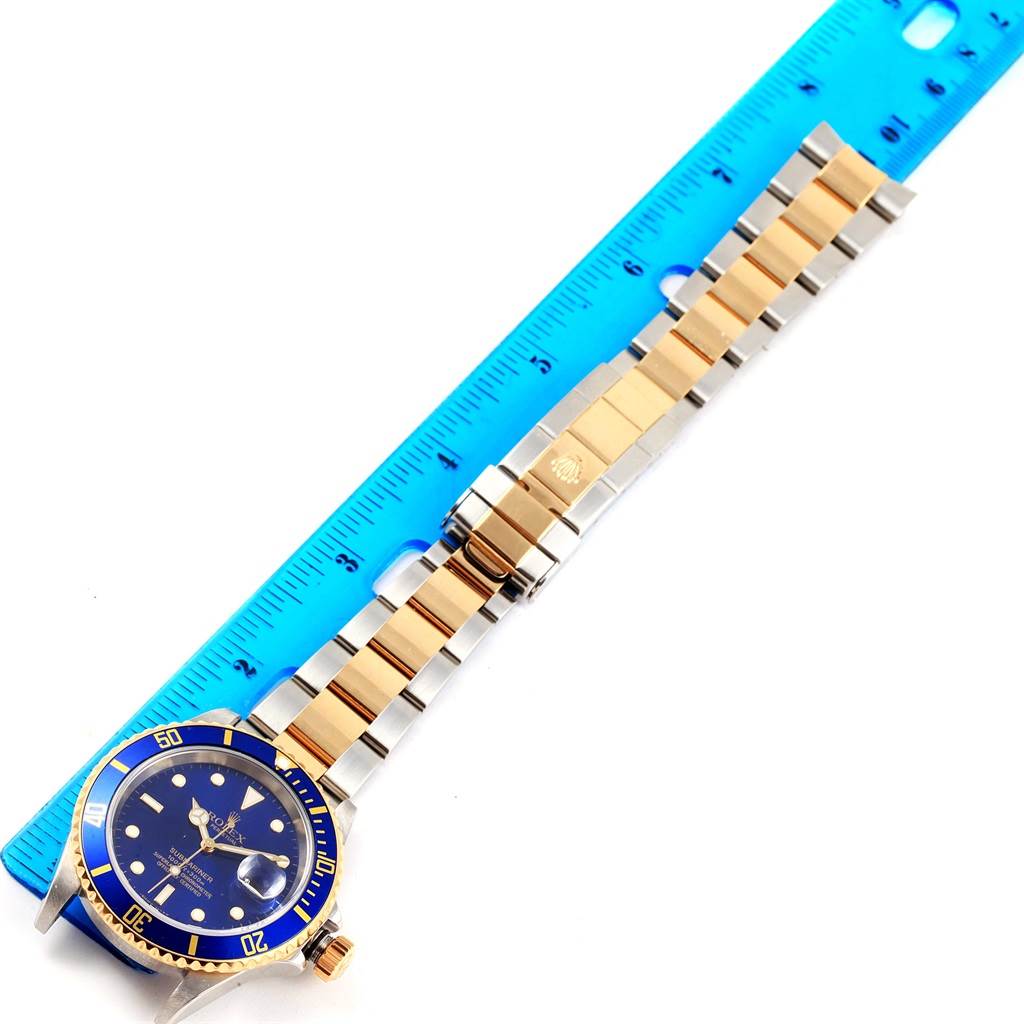 This image shows a Rolex Submariner 16613 Men's Steel and Gold (two tone) Blue Dial 16613 Men's Steel and Gold (two tone) Blue Dial watch laid flat, highlighting the dial, bezel, bracelet, and clasp, measured by a blue ruler.