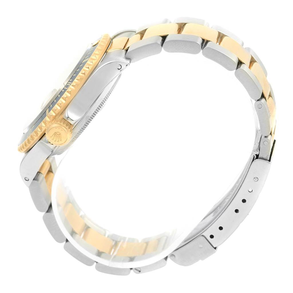 The image shows a side view of a Rolex Submariner 16613 Men
s Steel and Gold (two tone) Champagne Dial 16613 Men
s Steel and Gold (two tone) Champagne Dial watch focusing on its gold and silver bracelet and the crown.