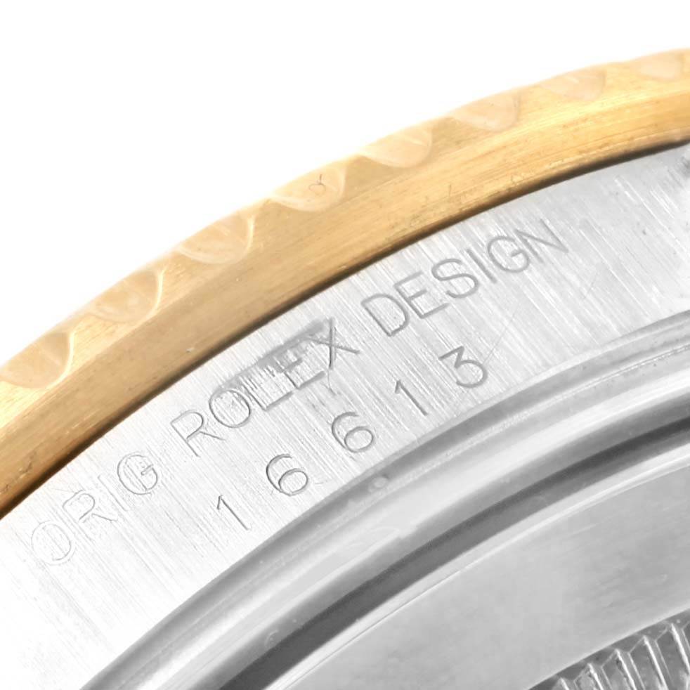 The image shows a close-up of the bezel and case back of the Rolex Submariner 16613 Men
s Steel and Gold (two tone) Champagne Dial 16613 Men
s Steel and Gold (two tone) Champagne Dial model, displaying the engraved model number.