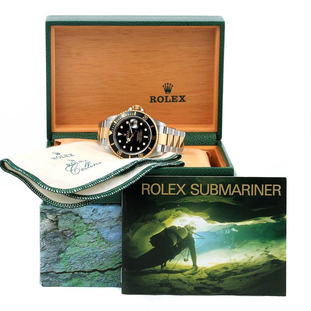The image shows a Rolex Submariner 16613 Men's Steel and Gold (two tone) Black Dial 16613 Men's Steel and Gold (two tone) Black Dial watch, its box, a cleaning cloth, and the manual, all from a frontal angle.