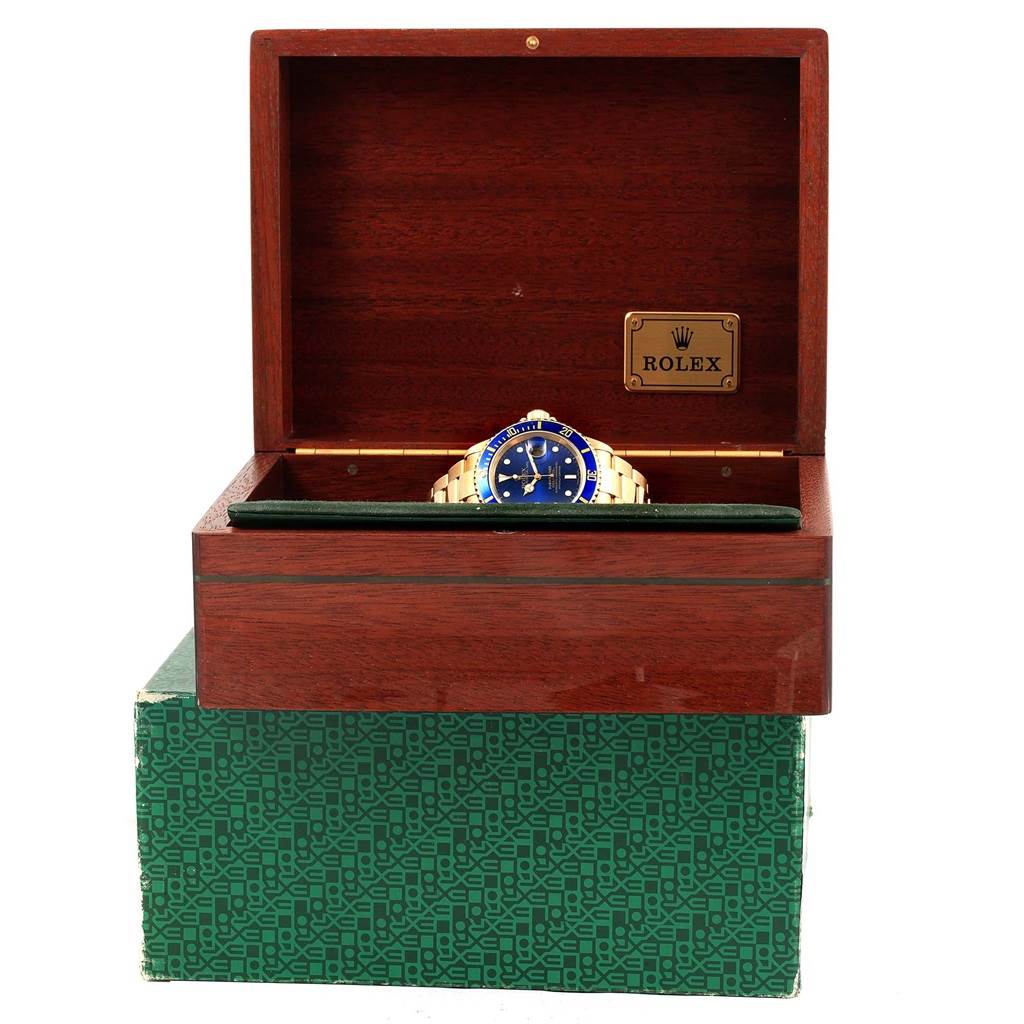 A Rolex Submariner 16618 Men's Yellow Gold Blue Dial 16618 Men's Yellow Gold Blue Dial model watch is shown inside an open wooden Rolex box, displayed from the front with the face and band visible.
