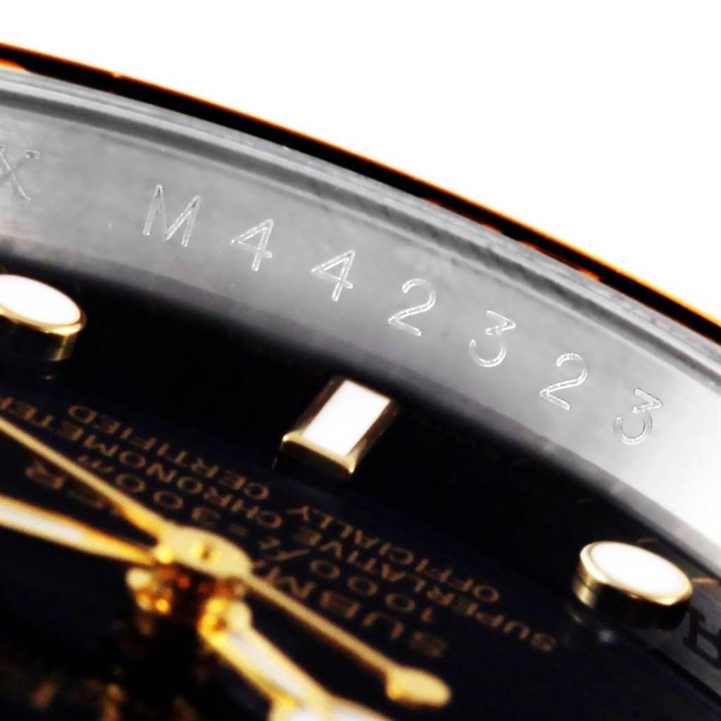 This close-up shot of the Rolex Submariner 16613 Men
s Steel and Gold (two tone) Black Dial 16613 Men
s Steel and Gold (two tone) Black Dial watch shows the engraved serial number on the inner bezel and part of the watch face.