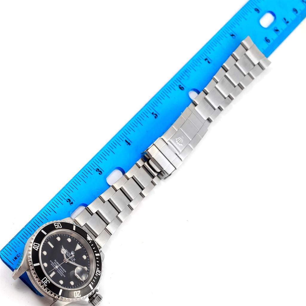 The image shows a Rolex Submariner 16610 Men's Stainless Steel Black Dial 16610 Men's Stainless Steel Black Dial watch from a top-down angle with the bracelet fully extended next to a blue ruler.
