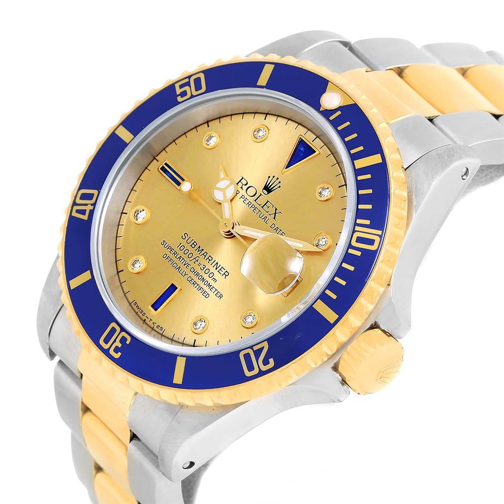 The image shows a Rolex Submariner 16613 Men
s Steel and Gold (two tone) Champagne Dial 16613 Men
s Steel and Gold (two tone) Champagne Dial watch at an angle displaying its gold and blue bezel, dial, crown, and bracelet.