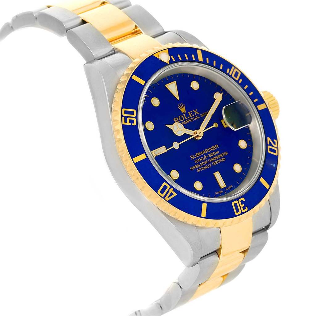 The image shows a Rolex Submariner 16613 Men's Steel and Gold (two tone) Blue Dial 16613 Men's Steel and Gold (two tone) Blue Dial watch at an angled view, showcasing its blue dial, bezel, and two-tone bracelet.