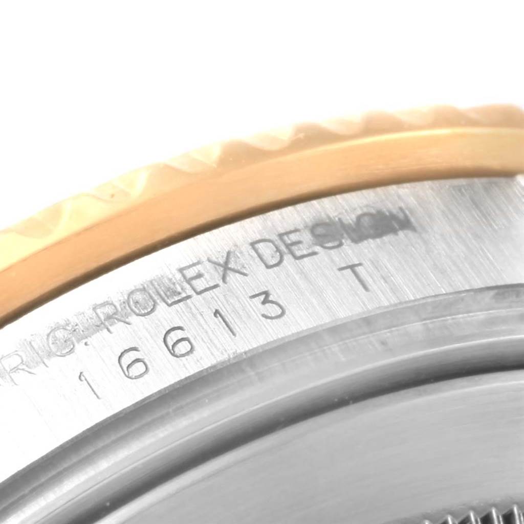 This close-up of a Rolex Submariner 16613 Men's Steel and Gold (two tone) Blue Dial 16613 Men's Steel and Gold (two tone) Blue Dial watch shows part of the bezel and the engraved model number "16613" on the case.