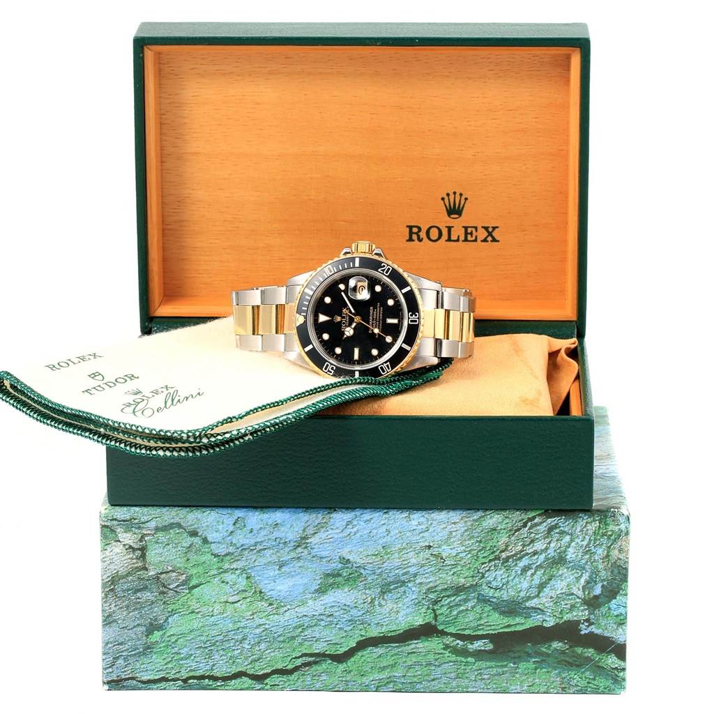 This image shows a Rolex Submariner 16803 Men's Steel and Gold (two tone) Black Dial 16803 Men's Steel and Gold (two tone) Black Dial watch displayed in an open green Rolex box with accompanying accessories.