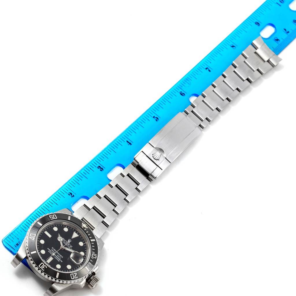 The image shows a Rolex Submariner 116610 Men's Stainless Steel Black Dial 116610 Men's Stainless Steel Black Dial watch laid flat with its full metal bracelet and clasp visible, next to a blue ruler for scale.