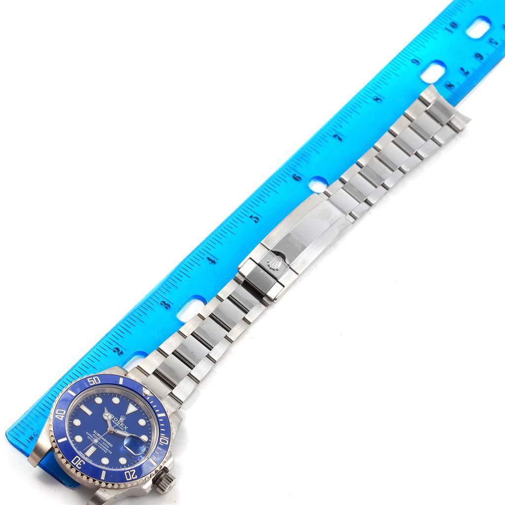 The image shows a Rolex Submariner 116619 Men's White Gold Blue Dial 116619 Men's White Gold Blue Dial watch laid flat with a blue bezel, metal bracelet, and clasp beside a ruler for scale.