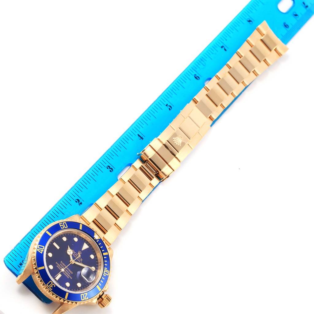The image shows a Rolex Submariner 16618 Men's Yellow Gold Blue Dial 16618 Men's Yellow Gold Blue Dial watch laid flat, measured against a blue ruler, displaying the face, bezel, and bracelet.