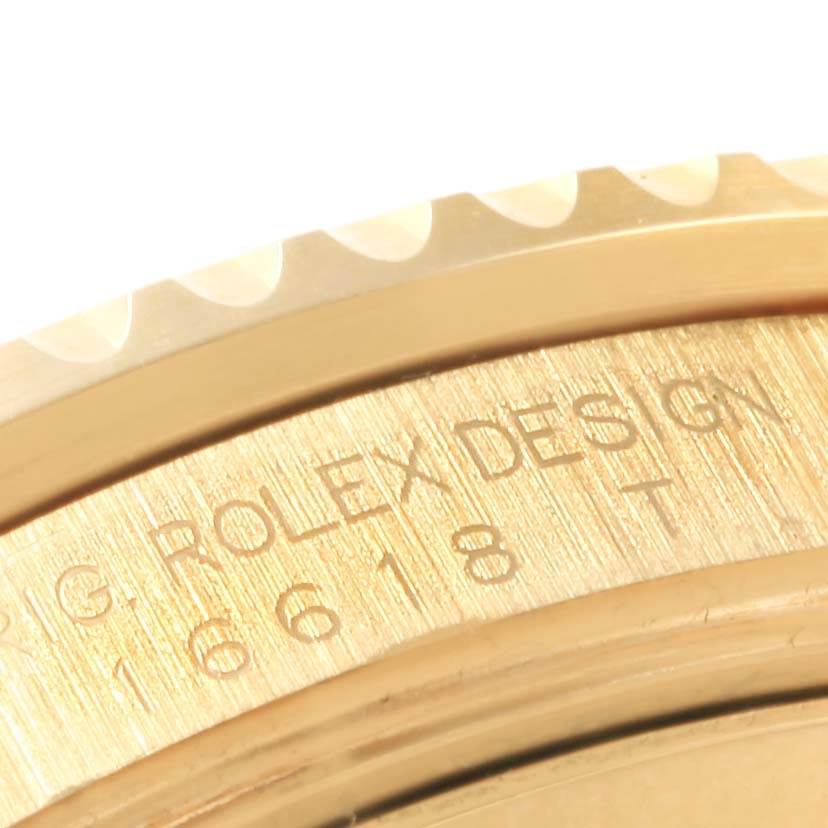 This image shows a close-up view of the engraved bezel and side casing of a Rolex Submariner 16618 Men's Yellow Gold Blue Dial 16618 Men's Yellow Gold Blue Dial watch.