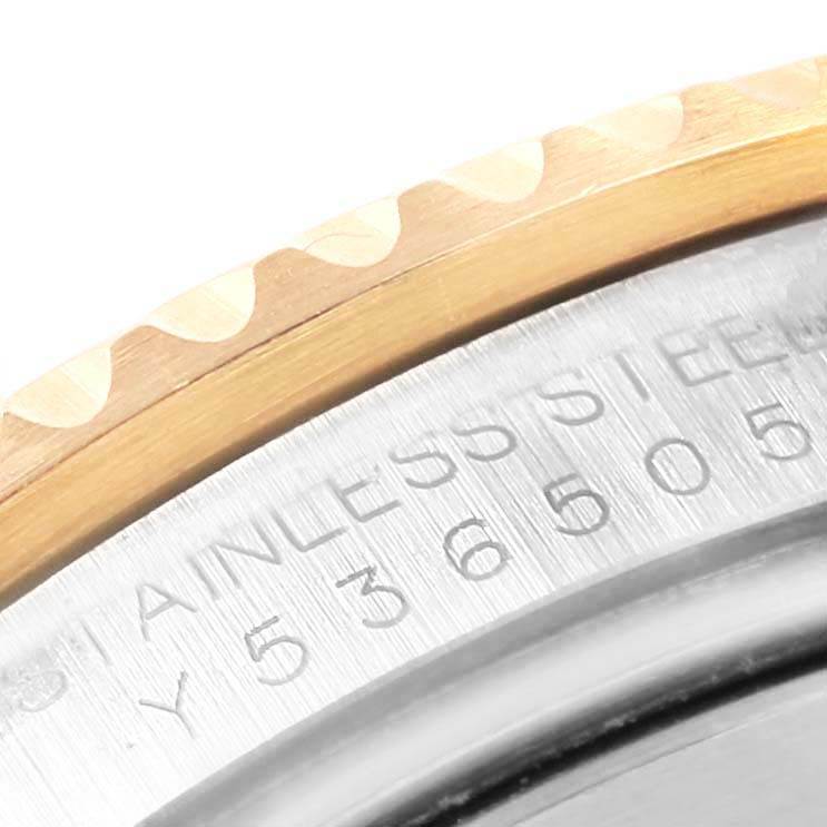 This close-up of a Rolex Submariner 16613 Men's Steel and Gold (two tone) Blue Dial 16613 Men's Steel and Gold (two tone) Blue Dial watch shows the gold-colored bezel and part of the stainless steel casing with engraved text.