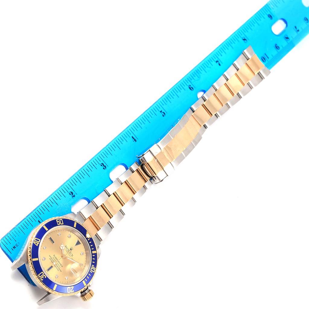 The image shows a flat-lay view of a Rolex Submariner 16613 Men's Steel and Gold (two tone) Champagne Dial 16613 Men's Steel and Gold (two tone) Champagne Dial watch, highlighting its gold and silver bracelet with a ruler for scale.