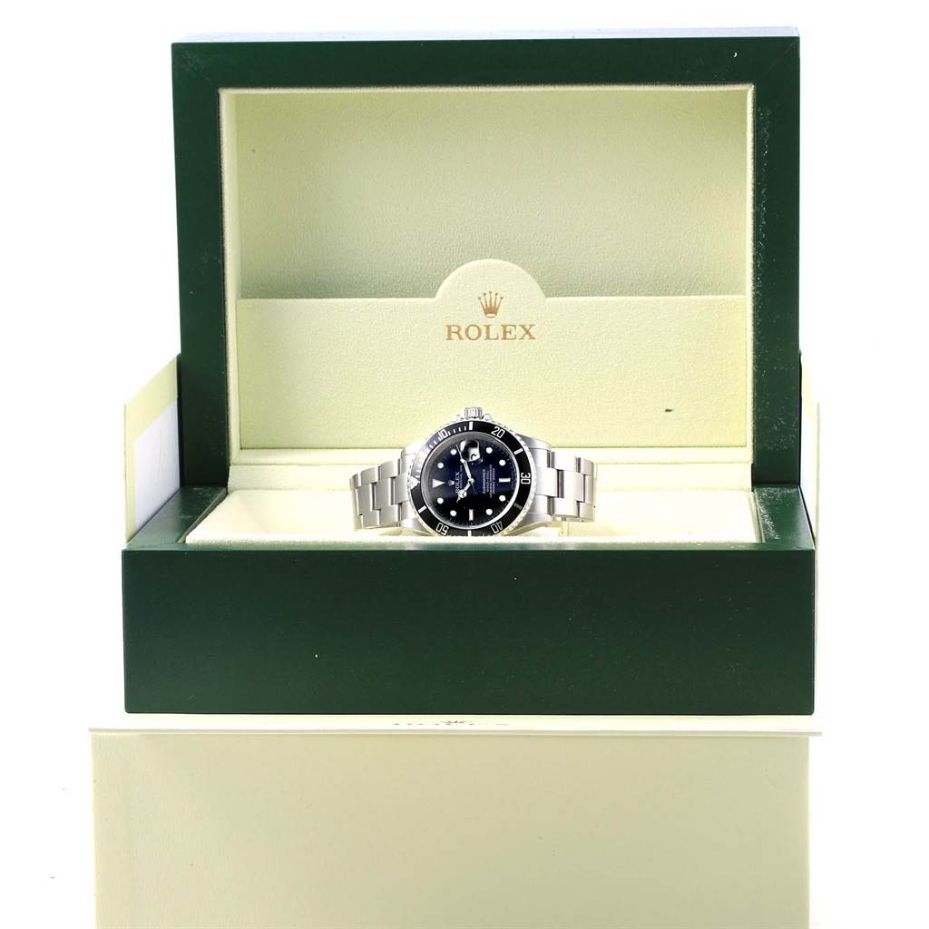 The Rolex Submariner 16610 Men's Stainless Steel Black Dial 16610 Men's Stainless Steel Black Dial watch is displayed front-on in its open green and cream box.