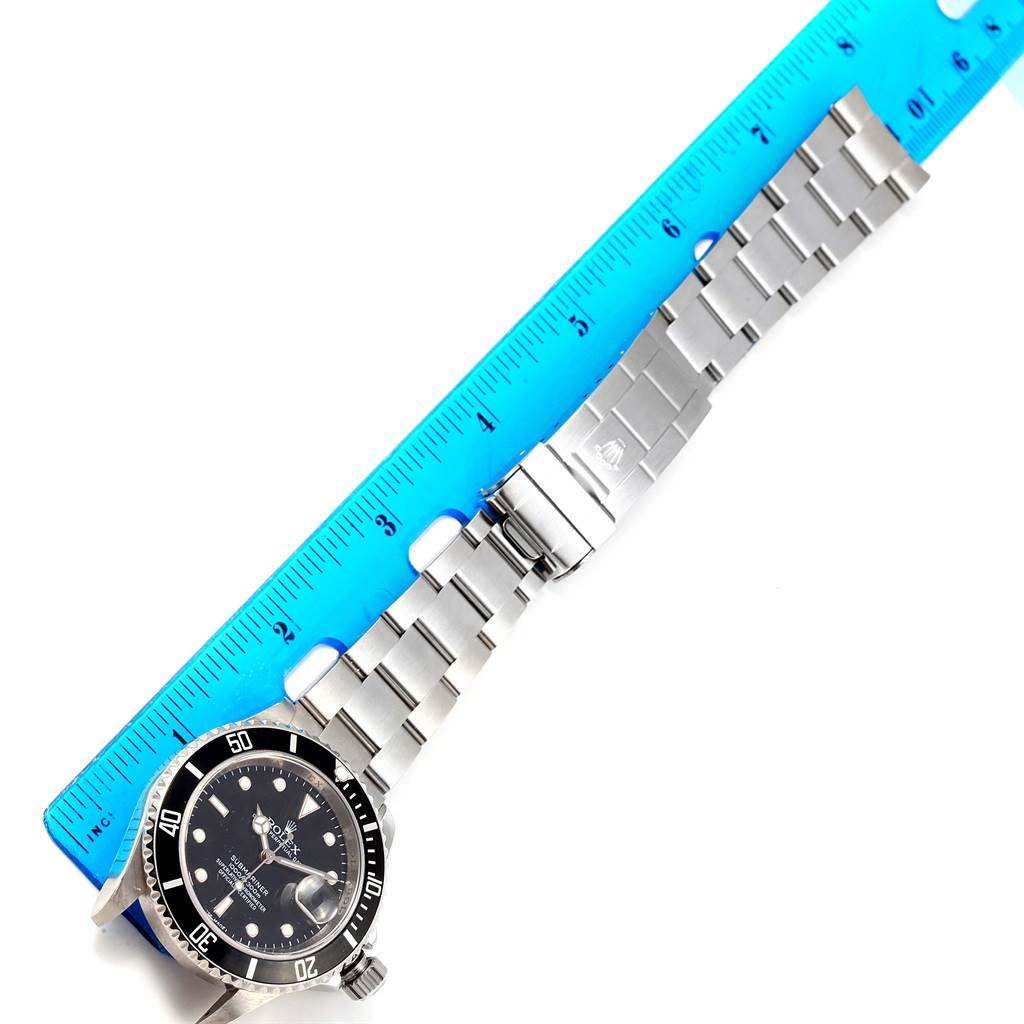 The image shows a Rolex Submariner 16610 Men's Stainless Steel Black Dial 16610 Men's Stainless Steel Black Dial watch laid flat, measured with a blue ruler; the face, bezel, and bracelet are visible.