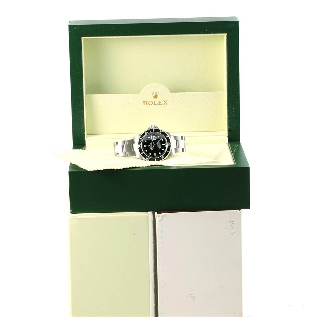 The Rolex Submariner 16610 Men's Stainless Steel Black Dial 16610 Men's Stainless Steel Black Dial watch is displayed front-on, inside an open green and cream box with the Rolex logo.