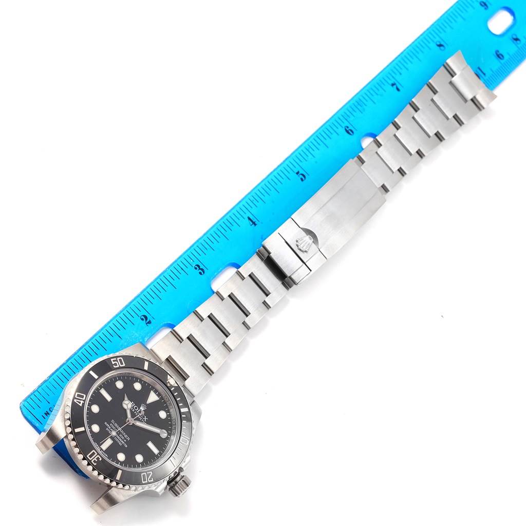 The image shows a Rolex Submariner 114060 Men's Stainless Steel Black Dial 114060 Men's Stainless Steel Black Dial watch laid flat next to a blue ruler, displaying the face, bezel, crown, and full bracelet.