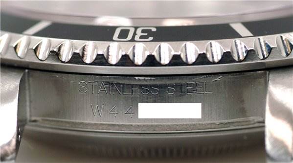 This close-up angle of the Rolex Submariner 16610 Men's Stainless Steel Black Dial 16610 Men's Stainless Steel Black Dial watch shows the stainless steel bezel and part of the serial number engraving.