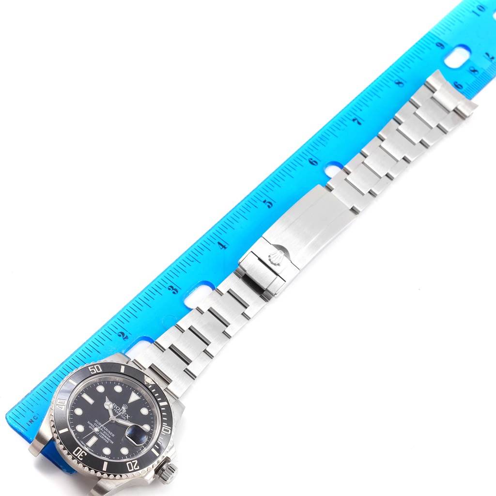 The image shows a Rolex Submariner 116610 Men's Stainless Steel Black Dial 116610 Men's Stainless Steel Black Dial watch laid flat alongside a ruler, displaying its dial, bezel, bracelet, and clasp.