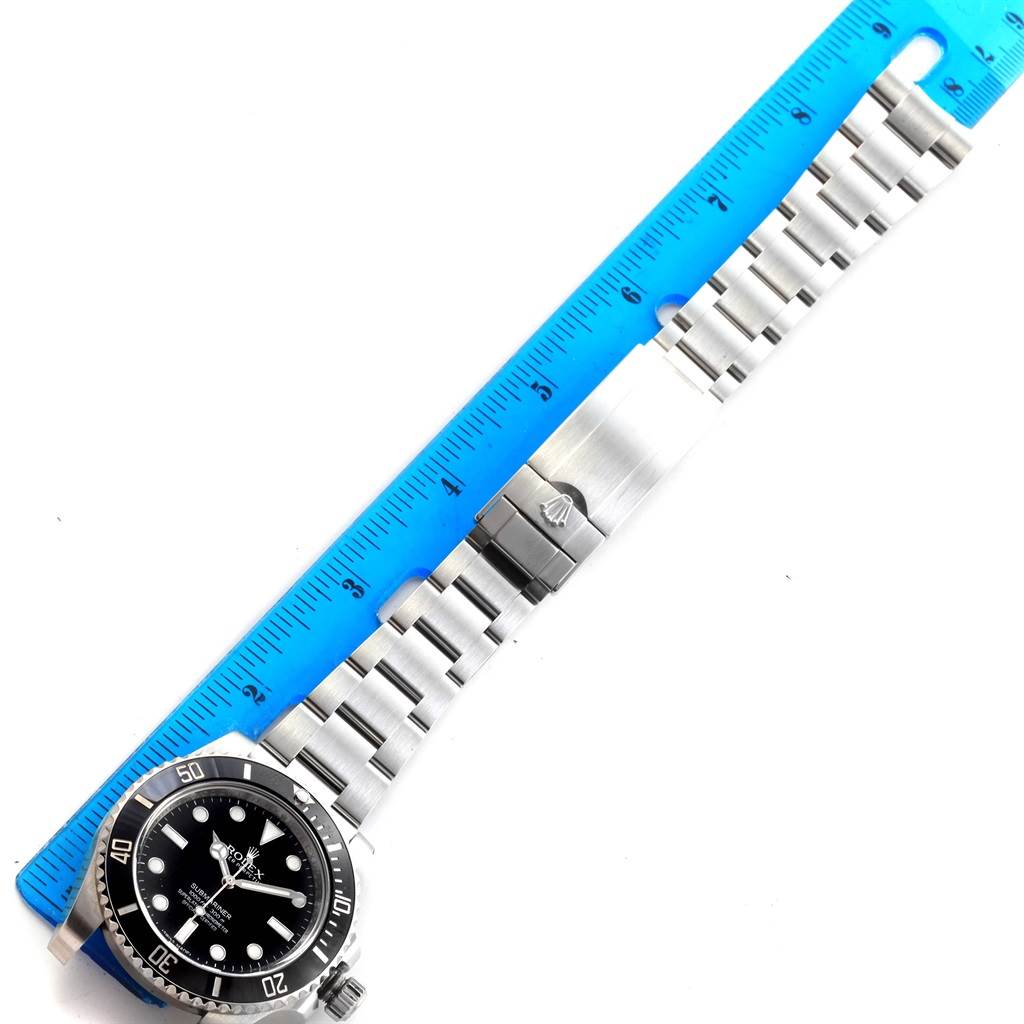 The Rolex Submariner 114060 Men's Stainless Steel Black Dial 114060 Men's Stainless Steel Black Dial watch is shown from a top-down angle, displaying the case, dial, bezel, and metal bracelet alongside a ruler.