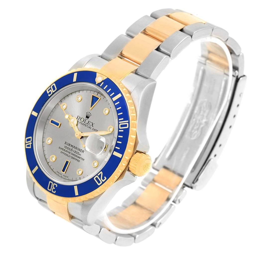 This image shows a Rolex Submariner 16613 Men's Steel and Gold (two tone) Grey Dial 16613 Men's Steel and Gold (two tone) Grey Dial watch at a slight angle, highlighting its blue and gold bezel, dial, and two-tone bracelet.