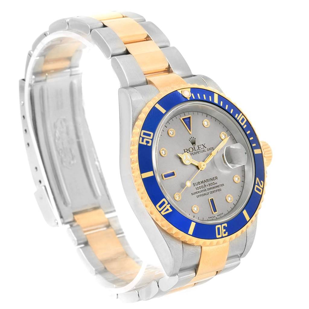 The Rolex Submariner 16613 Men's Steel and Gold (two tone) Grey Dial 16613 Men's Steel and Gold (two tone) Grey Dial watch is shown at a three-quarter angle, highlighting its blue bezel, gold accents, dial, and two-tone bracelet.