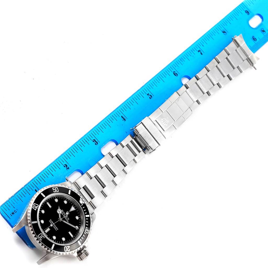 The image shows a Rolex Submariner 14060 Men's Stainless Steel Black Dial 14060 Men's Stainless Steel Black Dial watch laid flat next to a ruler, highlighting the watch's face, bracelet, and clasp.