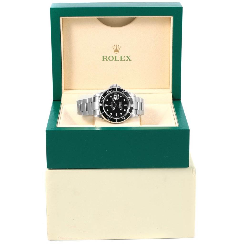 The Rolex Submariner 16610 Men's Stainless Steel Black Dial 16610 Men's Stainless Steel Black Dial watch is displayed front-on in its opened green and beige box.