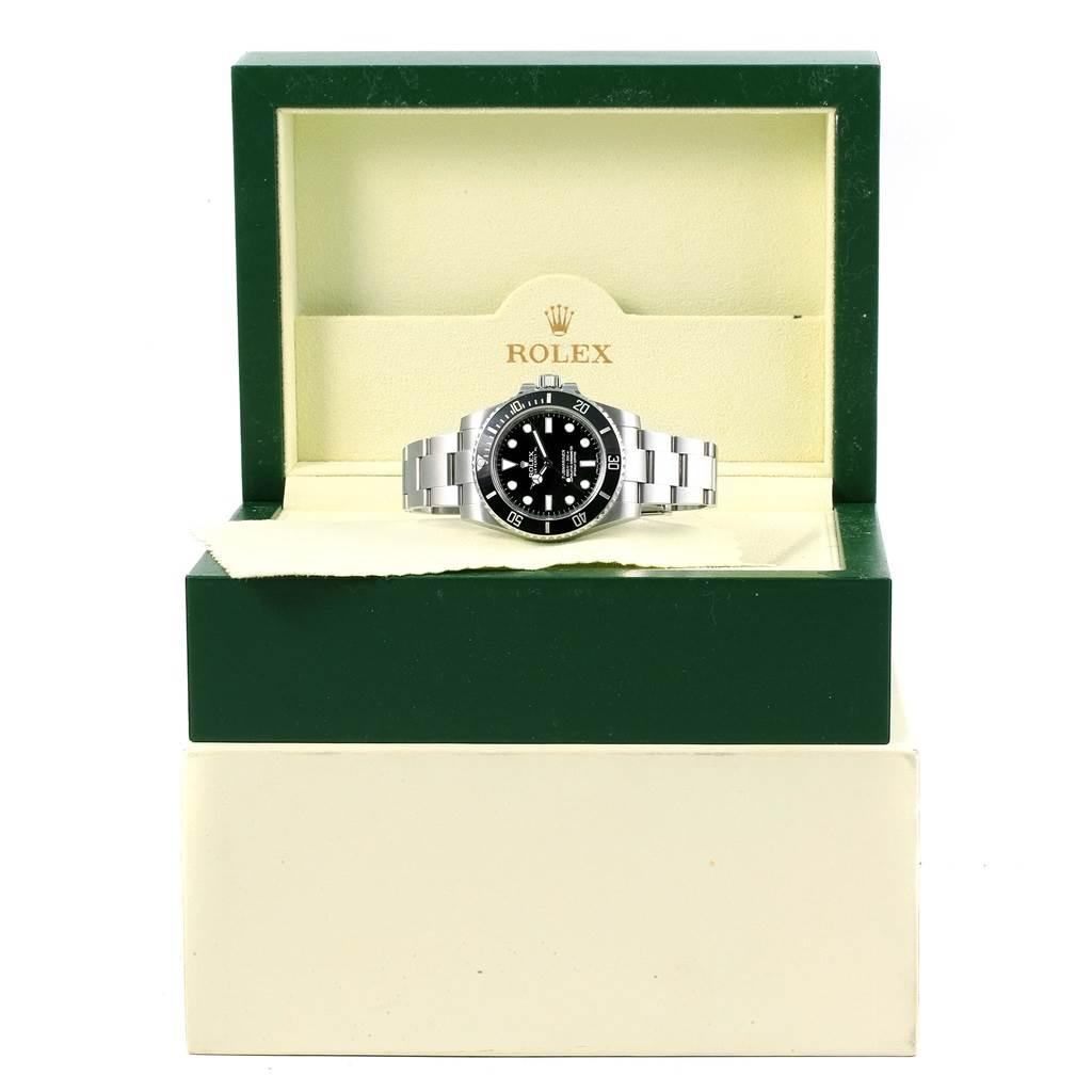 The Rolex Submariner 114060 Men's Stainless Steel Black Dial 114060 Men's Stainless Steel Black Dial watch is shown from the front, housed in an open green and beige branded box.