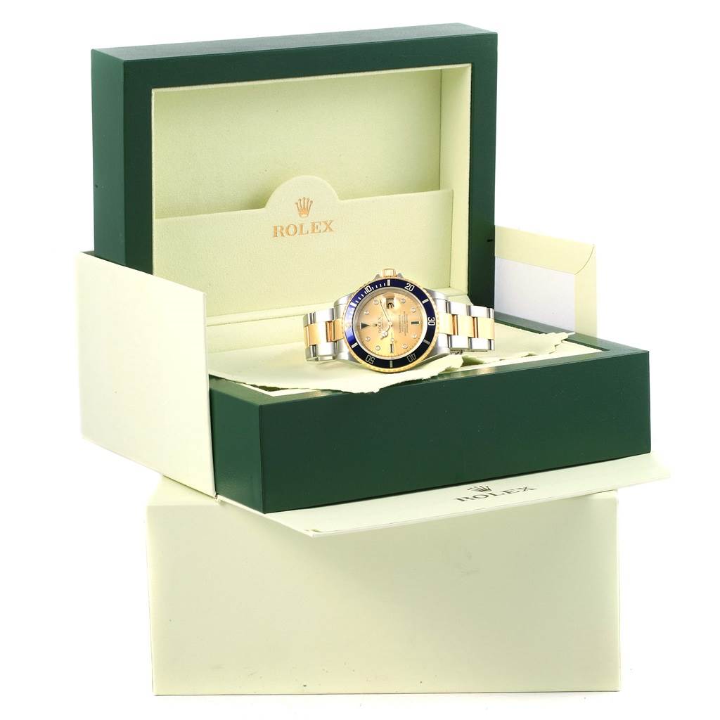 The Rolex Submariner 16613 Men's Steel and Gold (two tone) Champagne Dial 16613 Men's Steel and Gold (two tone) Champagne Dial watch is shown front-facing inside an open green and cream Rolex box.