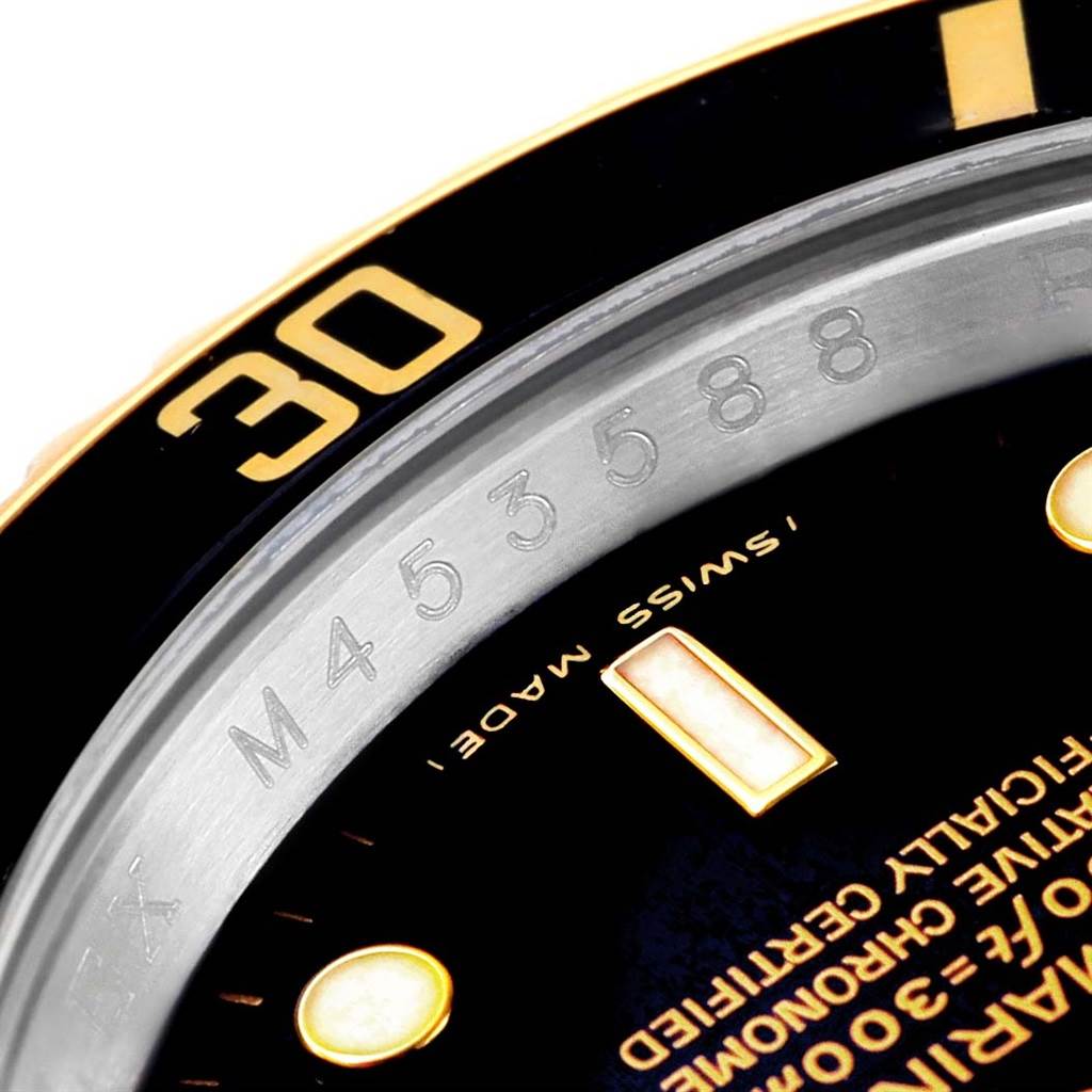 This close-up image shows part of the dial and bezel of a Rolex Submariner 16613 Men's Steel and Gold (two tone) Black Dial 16613 Men's Steel and Gold (two tone) Black Dial watch, including some engraved details.