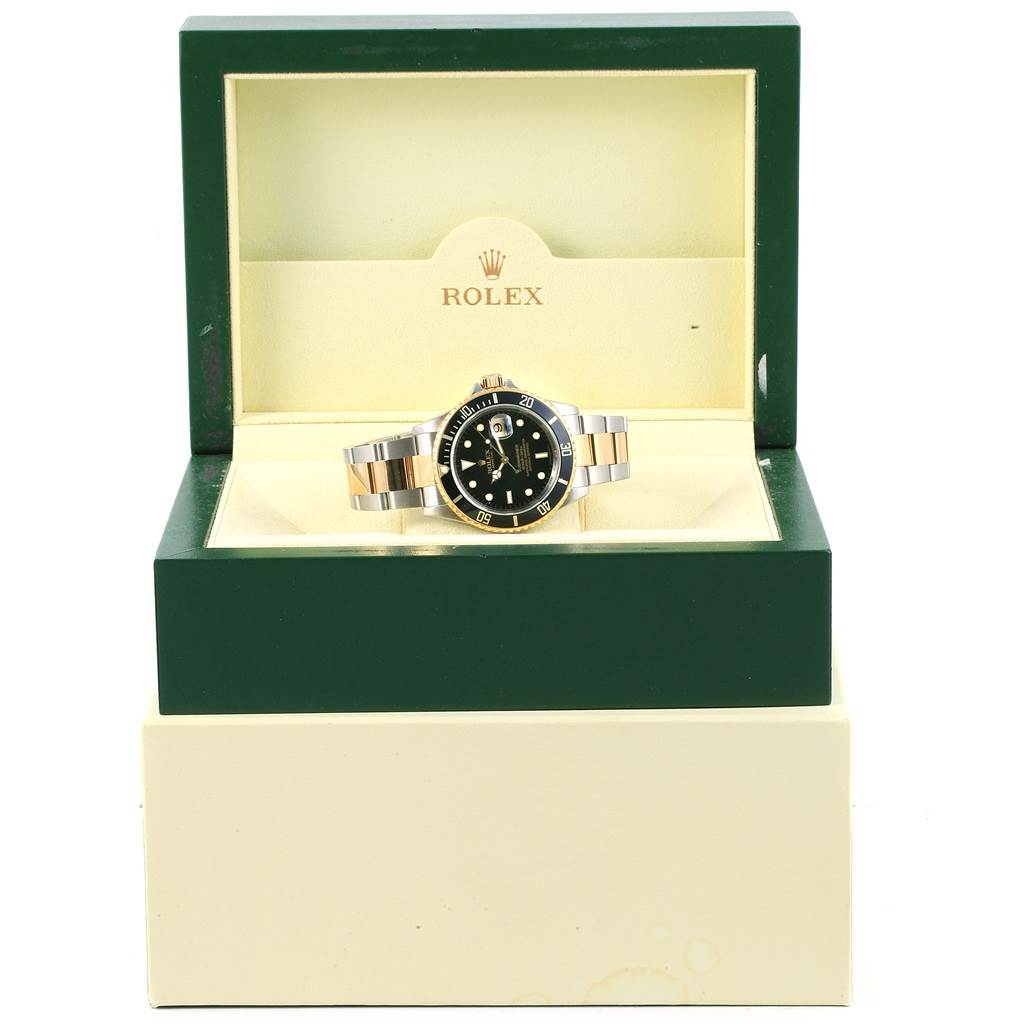 This image shows a Rolex Submariner 16613 Men's Steel and Gold (two tone) Black Dial 16613 Men's Steel and Gold (two tone) Black Dial watch in its open green and cream-colored box, displaying the face and bracelet from a front angle.