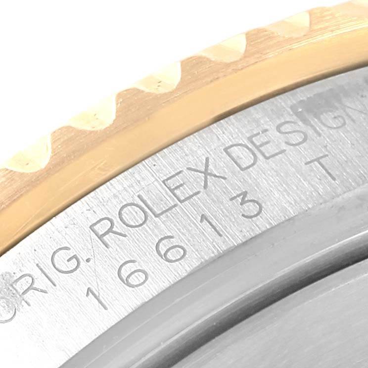 The image shows a close-up of the engraved text on the bezel and caseback of a Rolex Submariner 16613 Men's Steel and Gold (two tone) Black Dial 16613 Men's Steel and Gold (two tone) Black Dial watch.