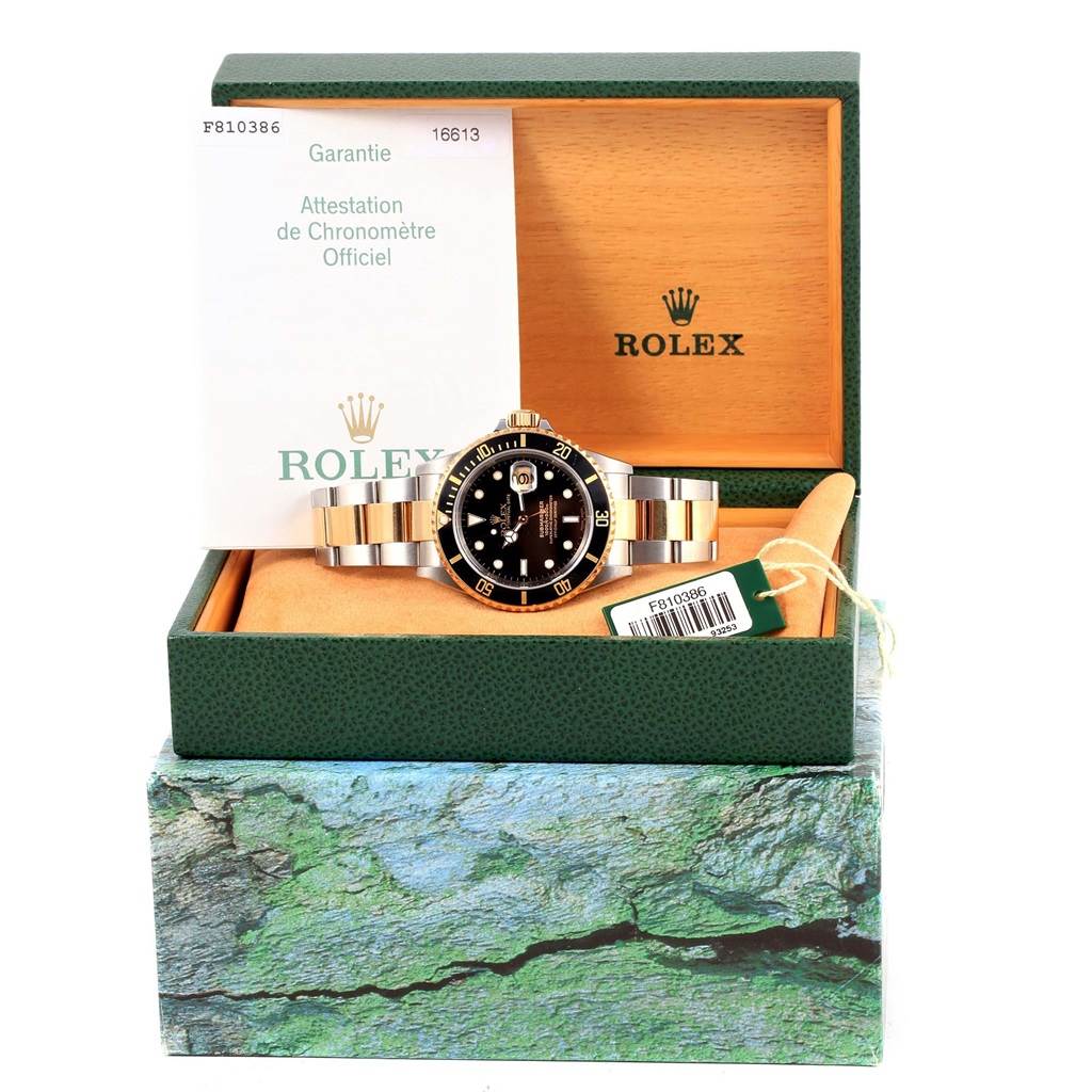 The image shows a front angle of the Rolex Submariner 16613 Men's Steel and Gold (two tone) Black Dial 16613 Men's Steel and Gold (two tone) Black Dial watch in its box, alongside the warranty and owner's manual.