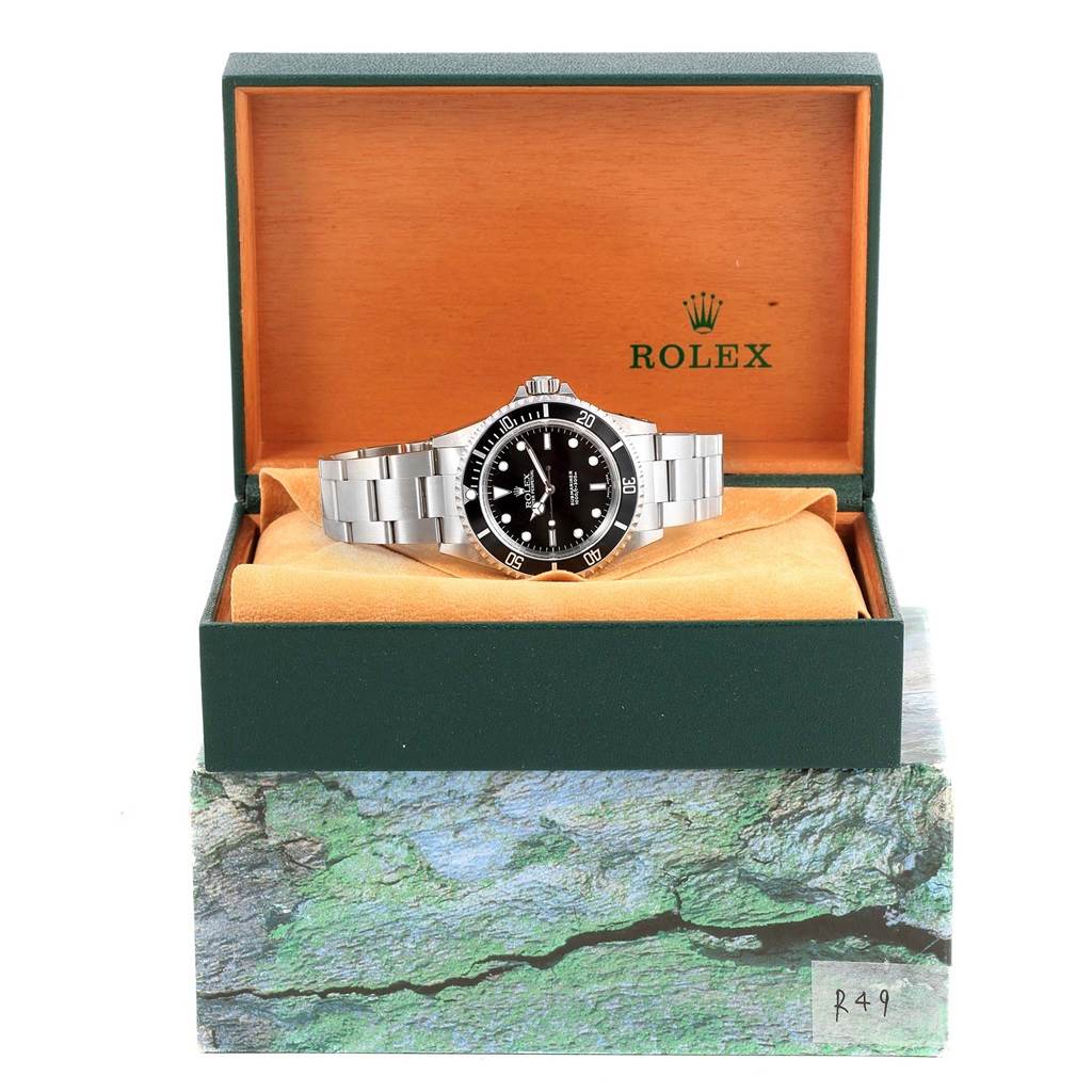 The Rolex Submariner 14060 Men's Stainless Steel Black Dial 14060 Men's Stainless Steel Black Dial watch is shown from the front, placed inside its open green and orange box.