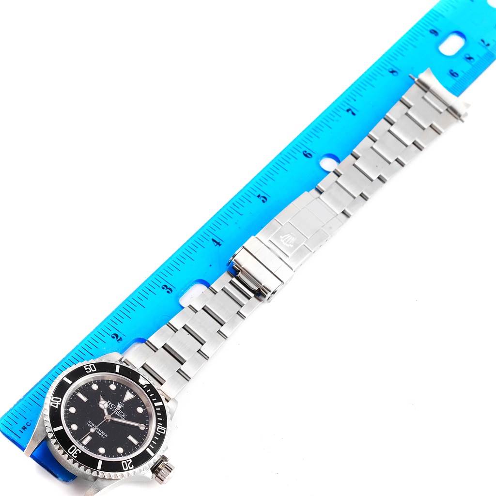 The Rolex Submariner 14060 Men's Stainless Steel Black Dial 14060 Men's Stainless Steel Black Dial watch is shown from an overhead angle, displaying its bracelet and clasp beside a measuring ruler.