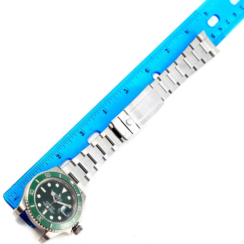 This image shows a top view of a Rolex Submariner 116610LV Men's Stainless Steel Green Dial 116610LV Men's Stainless Steel Green Dial watch with its stainless steel bracelet fully extended next to a blue ruler.