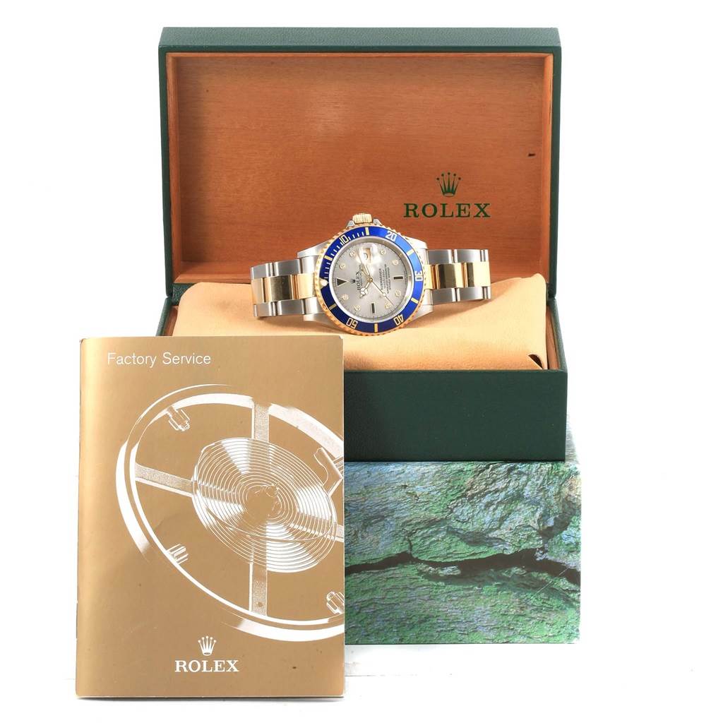 The Rolex Submariner 16613 Men's Steel and Gold (two tone) Grey Dial 16613 Men's Steel and Gold (two tone) Grey Dial watch is displayed in its open box with a factory service booklet beside it.