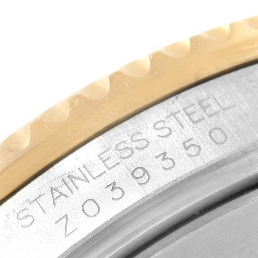 The image shows a close-up of the edge of a Rolex Submariner 16613 Men's Steel and Gold (two tone) Grey Dial 16613 Men's Steel and Gold (two tone) Grey Dial watch with visible engravings on the stainless steel case.