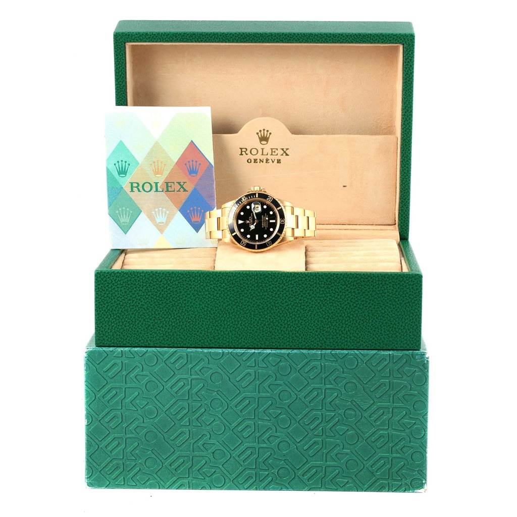 The image shows a Rolex Submariner 16618 Men
s Yellow Gold Black Dial 16618 Men
s Yellow Gold Black Dial watch in its open green box, displaying the watch and accompanying booklet.