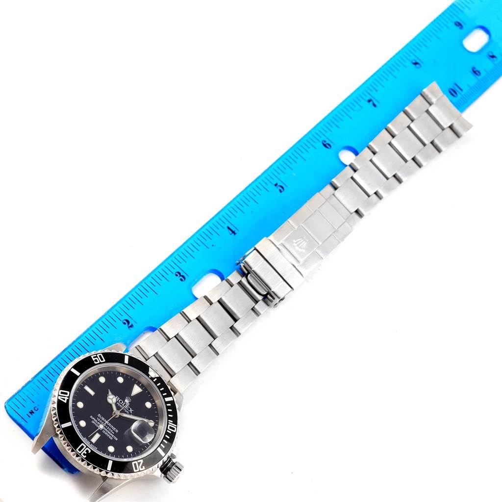 The image shows a Rolex Submariner 16610 Men's Stainless Steel Black Dial 16610 Men's Stainless Steel Black Dial watch laid flat with its bracelet extended beside a ruler.