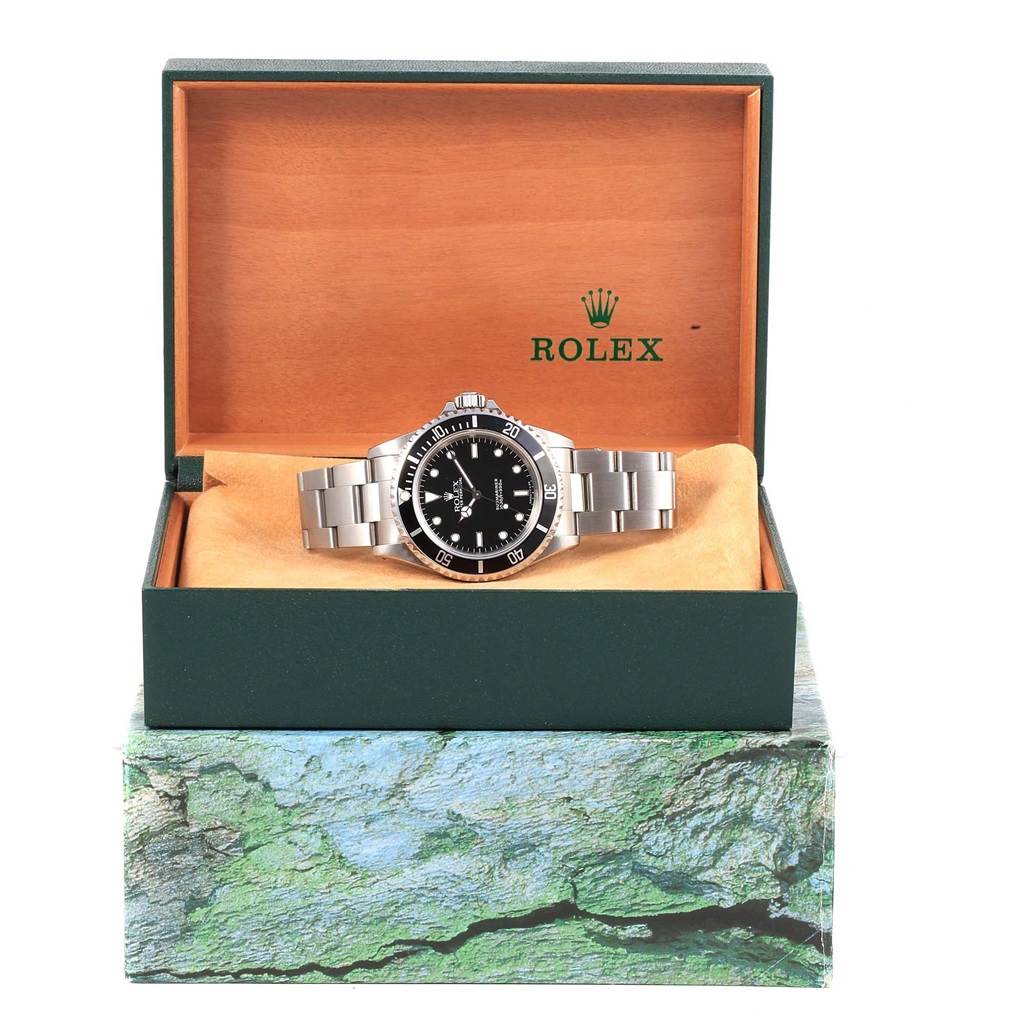 The Rolex Submariner 14060 Men's Stainless Steel Black Dial 14060 Men's Stainless Steel Black Dial watch is shown front-on, placed in an open green box with the logo visible in the background.
