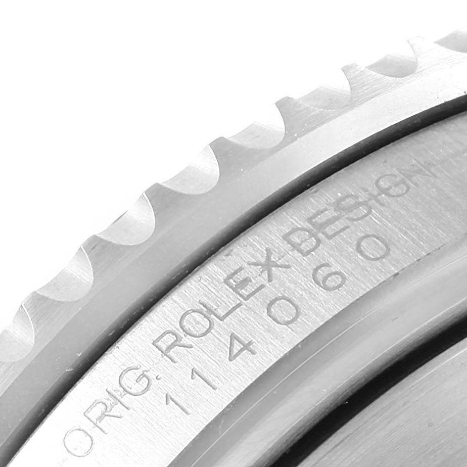 The image shows a close-up angle of the bezel and part of the case, including serial engravings, on a Rolex Submariner 114060 Men's Stainless Steel Black Dial 114060 Men's Stainless Steel Black Dial watch.