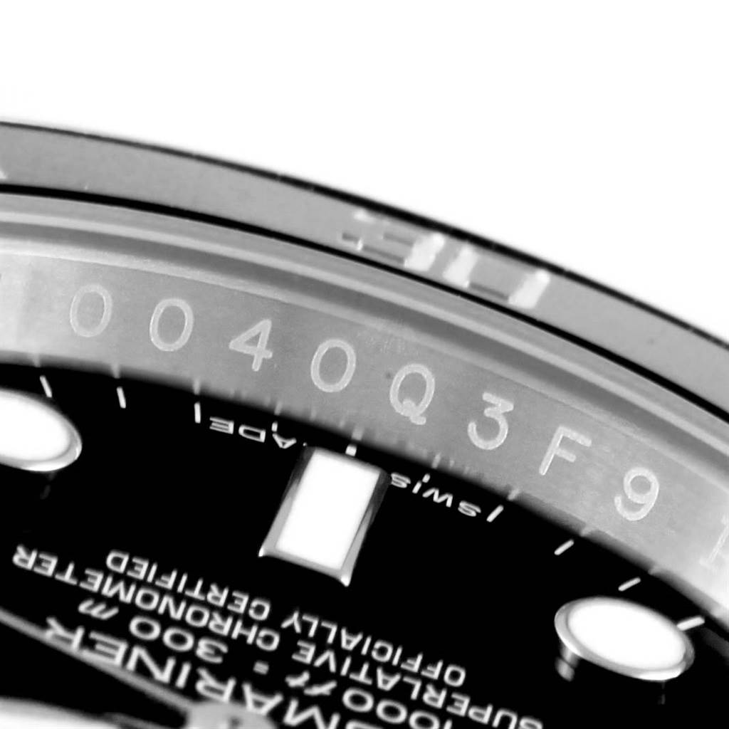 The image shows a close-up of the bezel and part of the dial of a Rolex Submariner 114060 Men's Stainless Steel Black Dial 114060 Men's Stainless Steel Black Dial watch, highlighting some serial numbers.